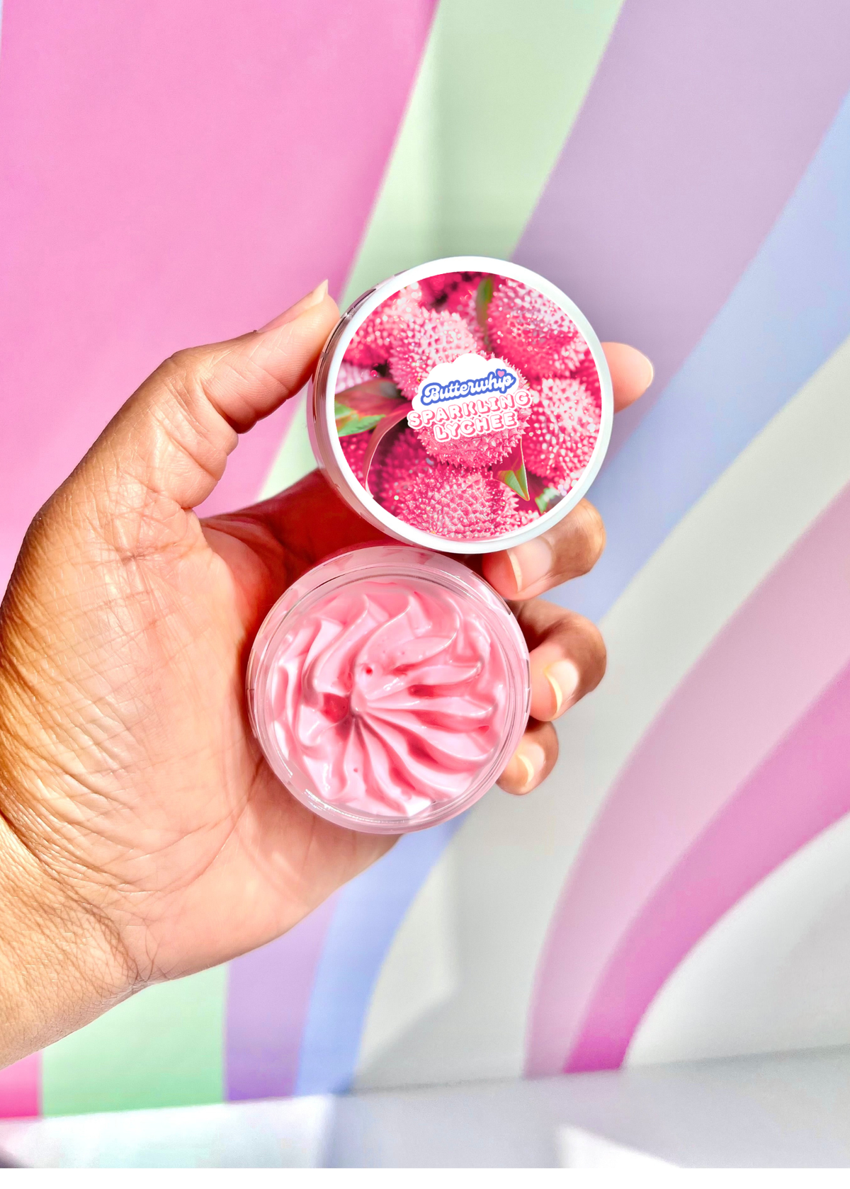 Hand holding 1 oz jar of Sparkling Lychee Body Butter Cream